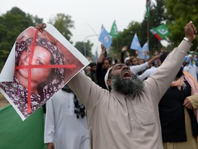 A Pakistani supporter of the Ahle Sunnat Wal Jamaat (ASWJ), a hardline religious party, holds an image of Christian woman Asia Bibi during a protest rally following the Supreme Court's decision to acquit Bibi of blasphemy, in Islamabad on November 2, 2018.