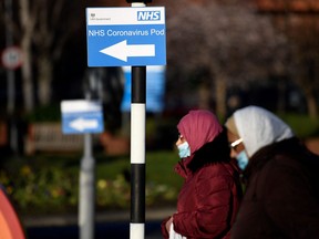 Pedestrians walk past a sign for a NHS Coronavirus Pod outside St. James's University Hospital in Leeds, northern England on Jan. 5, 2022, where a temporary "Nightingale" COVID-19 surge hub to treat patients with coronavirus is to be set up.