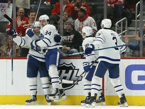 Toronto Maple Leafs left wing Michael Bunting, left, celebrates with centre Auston Matthews (34), right wing Mitchell Marner (16) and defenscman Justin Holl (3) after scoring his third goal of the game during the third period of an NHL hockey game Saturday against the Detroit Red Wings, Jan. 29, 2022, in Detroit.
