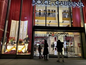 People stand outside the Dolce & Gabbana store on Fifth Avenue, Nov. 21, 2021, in New York.