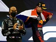 Red Bull's Max Verstappen celebrates winning the race and the world championship with the Netherlands flag on the podium as Mercedes' Lewis Hamilton looks on after finishing second.