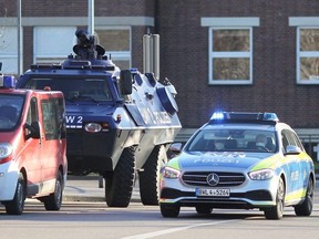 An armoured police vehicle stands next to a police car on the compound of the University of Heidelberg, in southwestern Germany, after an attack by a lone gunman, Monday, Jan. 24, 2022.