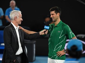 Former US tennis player John McEnroe (L) interviews Serbia's Novak Djokovic after his victory against Germany's Jan-Lennard Struff in their men's singles match on day one of the Australian Open tennis tournament in Melbourne on January 20, 2020. (Photo by WILLIAM WEST/AFP via Getty Images)