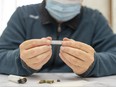 Man with a mask preparing a marijuana cigarette with rolling paper.