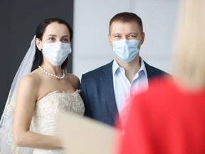 Man and woman in wedding suits and medical protective masks at ceremony. Weddings in coronavirus pandemic concept