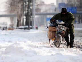 In this file photo, a postal worker makes his way along a snow-covered street after heavy snowfall in Beijing on Jan. 4, 2010.