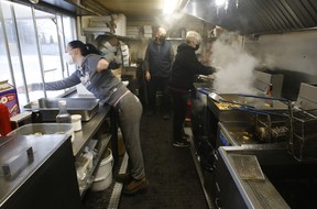 On a cold January morning, Faith Weston (left) hands off some lunch to customers while Heather O’Leary (right) works the steamy fries vat as Victor Hanc looks on inside the famous Hanc’s Fries food truck in Bowmanville.