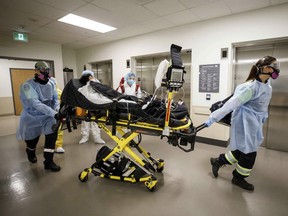 Paramedics and healthcare workers transfer a patient from Humber River Hospital's Intensive Care Unit to a waiting air ambulance as the hospital frees up space In their ICU unit, in Toronto on April 28, 2021.