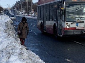 A pedestrian walks on the road next to a snowbank in the Kingston Rd.-Fenwood Heights area. SCOTT LAURIE / TORONTO SUN