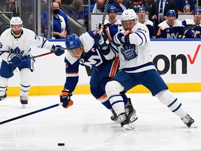 L'ailier gauche des Islanders de New York Anders Lee et le défenseur des Maple Leafs de Toronto Travis Dermott se battent pour une rondelle libre au cours de la deuxième période à l'UBS Arena à Elmont, NY, le 22 janvier 2022.