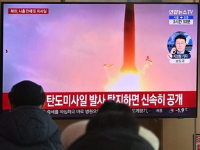 People watch a TV screen showing a news broadcast with file footage of a North Korean missile test, at a railway station in Seoul, South Korea, Sunday, Jan. 30, 2022, after North Korea fired a "suspected ballistic missile" in the country's seventh weapons test this month, according to the South's military.