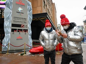 Two men walk past a countdown installation for the Beijing 2022 Winter Olympic Games which begin in two weeks time, in Beijing on January 20, 2022.