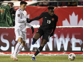 Canada's Alphonso Davies (19) and Mexico's Julio Cesar Domingguez Juarez (3) via for the ball during World Cup Qualifiers in Edmonton, Tuesday, Nov. 16, 2021.