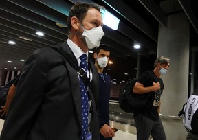 Serbian tennis player Novak Djokovic, centre,  walks in Melbourne Airport before boarding a flight, after the Federal Court upheld a government decision to cancel his visa to play in the Australian Open,  January 16, 2022.