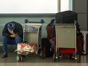 A passenger sits with luggage at John F. Kennedy International Airport during the spread of the Omicron coronavirus variant in Queens, New York City, Dec. 26, 2021.