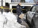 Ein Polizist aus Toronto bringt am Donnerstag, dem 20. Januar 2022, dem Tag nach der tödlichen Erschießung des 15-jährigen Jordon Carter, eine Beweismitteltasche in die Tiefgarage in der Gamble Ave. 72.  