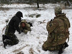 Ukrainian civilians learn to build a shelter in deep snow as part of a crash course in survival skills, in a forest on the outskirts of Kiev on January 30, 2022.