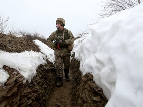 An Ukrainian Military Forces serviceman walks in a trench on the frontline with Russia-backed separatists near Luganske village, in Donetsk region, Tuesday, Jan. 11, 2022.