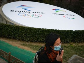 A woman using her mobile phone walks past an installation promoting the Beijing 2022 Winter Olympic and Paralympic Games in Beijing on January 19, 2022.