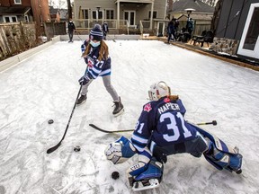 Riley Napier, 9, in goal, and Miyoko Hogeveen ,10, enjoy a backyard ice rink in Brampton, Ont. on Saturday, Jan. 8, 2022.