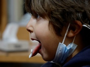 A medical worker administers a COVID-19 saliva test to a 5-year-old child at a testing centre in Nice, France, Thursday, Jan. 13, 2022.