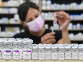 CP-Web.  Barbara Violo, pharmacist and owner of The Junction Chemist Pharmacy, draws up a dose behind vials of both Pfizer-BioNTech and Oxford-AstraZeneca COVID-19 vaccines on the counter, in Toronto, Friday, June 18, 2021.