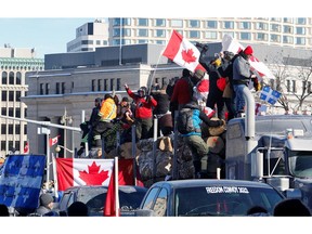 Protesters stand on a trailer carrying logs as truckers and supporters take part in a convoy to protest COVID-19 vaccine mandates for cross-border truck drivers in Ottawa, Jan. 29, 2022.