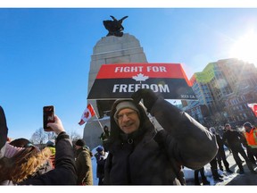 Ein Mann posiert für ein Foto vor dem National War Memorial, während Trucker und Unterstützer an einem Konvoi teilnehmen, um gegen COVID-19-Impfstoffmandate für grenzüberschreitende Lkw-Fahrer in Ottawa, Ontario, Kanada, am 29. Januar 2022 zu protestieren.