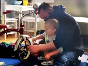 Jacob Whaley and his 2-year-old son, Dawson, pretend to repair a tricycle together.