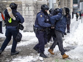 A person is pictured being taken into custody by Ottawa Police as officers clear the downtown core of “Freedom Convoy” protesters on Feb. 20, 2022.