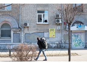 Ein Mann geht am 26. Februar 2022 in Kiew an einem Haus mit zerbrochenem Fenster im Gebiet Solomianska vorbei.