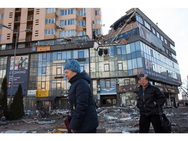 Women pass by the apartment block in 6A Lobanovsky Avenue which was hit with a missile on Feb. 26, 2022 in Kyiv.