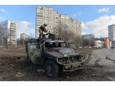 An Ukrainian Territorial Defence fighter examines a destroyed Russian infantry mobility vehicle GAZ Tigr after the fight in Kharkiv on Feb. 27, 2022.