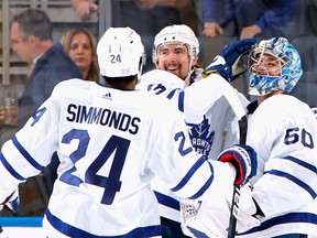Joseph Woll of the Toronto Maple Leafs celebrates his first NHL shutout, a 3-0 victory against the New York Islanders at the UBS Arena on November 21, 2021 in Elmont, New York, with teammates Wayne Simmonds and Justin Holl.