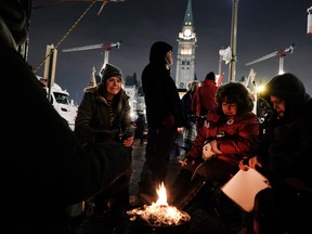 People keep warm by a fire as part of a convoy of truck protesters against COVID-19 mandates on February 9, 2022 in Ottawa. Spencer Platt/Getty Images