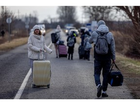 Menschen gehen mit ihren Habseligkeiten nach dem Grenzübertritt in Barabas-Koson, als sie am 26. Februar 2022 in Barabas, Ungarn, aus der Ukraine fliehen.