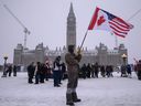 Ein Demonstrant hält am 12. Februar 2022 vor dem kanadischen Parlament in Ottawa eine US-amerikanische und eine kanadische Flagge während eines Protestes von Lkw-Fahrern gegen COVID-19-Mandate.