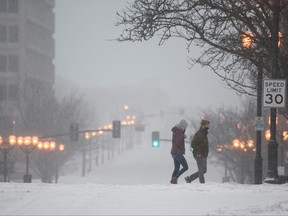 People walk through empty streets during a snowstorm in Clayton, Miss., Feb. 3, 2022.