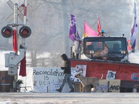 A First Nations protester walks in front of a snowplow blade as part of a train blockade in Tyendinaga, near Belleville, Ont. on February 21, 2020. The blockades were put in place in solidarity with Wet'suwet'en First Nation hereditary chiefs who oppose a natural gas pipeline in their traditional territory in B.C.