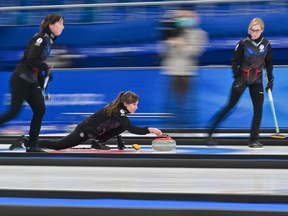 Russia's Olympic Committee Alina Kovaleva (C) curls the stone as Galina Arsenkina (R) and Ekaterina Kuzmina (L) watch during the women's round robin of the Beijing 2022 Winter Olympic Games against Britain on February 17, 2022.