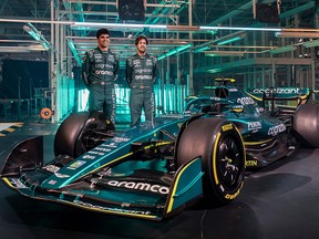 A handout picture released by Aston Martin shows Formula One drivers Lance Stroll and Sebastian Vettel (R) posing with the new AMR22 car during its presentation at the global headquarters of Aston Martin Lagonda in Gaydon on February 10, 2022.