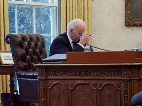 U.S. President Joe Biden is seen through a glass doorway as he speaks by phone with Ukraine's President Volodymyr Zelenskiy in the Oval Office at the White House in Washington, December 9, 2021.