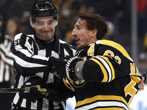 Boston Bruins winger Brad Marchand (63) is held back by linesman Andrew Smith (51) after he got a penalty for attempting to injure against the Pittsburgh Penguins at TD Garden.