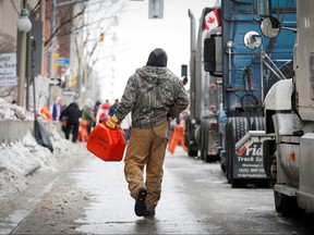 A trucker carries a gas canister with "Freedom of Choice" written on it, as truckers and supporters continue to protest COVID-19 vaccine mandates, in Ottawa, Feb. 9, 2022.
