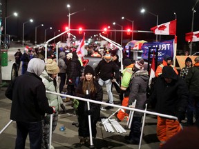 People erect a tent as truck drivers and supporters continue to block access to the Ambassador Bridge, which links Detroit and Windsor, in protest against COVID-19 vaccine mandates, in Windsor, Ont., Feb. 10, 2022.