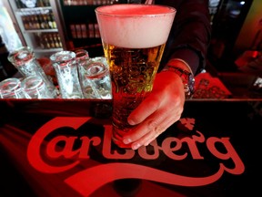 A bartender holds a glass of Carlsberg beer in a bar in St. Petersburg June 17, 2014.