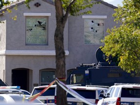 Multiple holes in windows can be seen at a house where Phoenix Police Department officers were shot after responding to a shooting inside the home Friday, Feb. 11, 2022, in Phoenix.