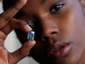 Model Stephany Martins holds up the "The De Beers Cullinan Blue" blue diamond during a press preview at Sotheby's in New York, on February 15, 2022.