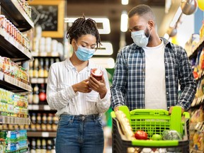 This photo depicts a couple obeying masking rules while shopping for groceries