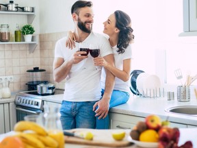 Excited happy beautiful young couple in love cooking in the kitchen and having fun together while making fresh healthy fruits salad